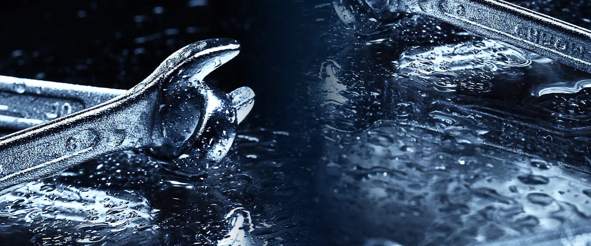 Close-up of professional combination wrenches on a wet steel surface
